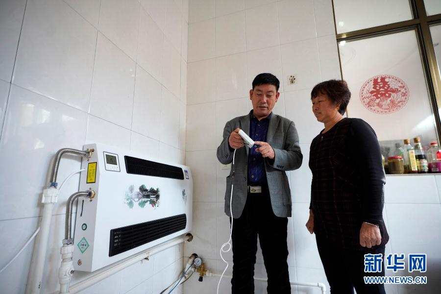 河北省隆尧县杨河村村委会委员王梦云(左)在给村民魏贵芬讲解电采暖设备的使用方法(2019年10月31日摄)。新华社记者 邢广利 摄